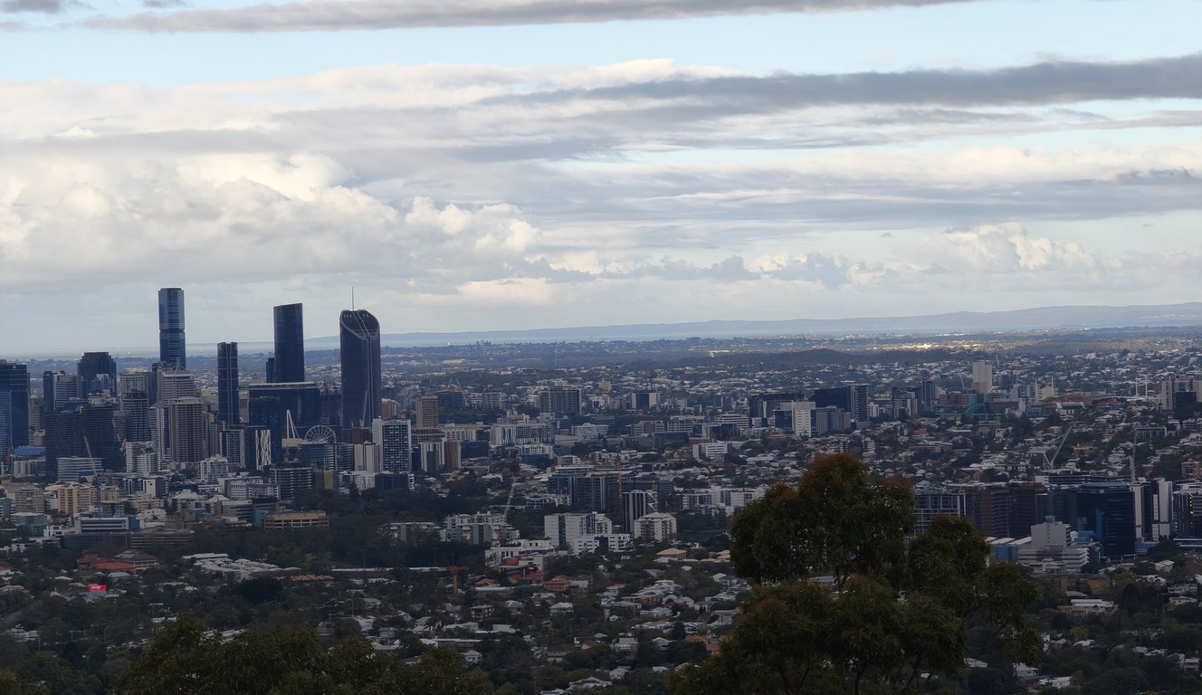 Brisbane city skyline under heavy grey rain clouds, seen from the Mt Coot-tha lookout